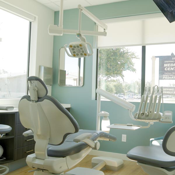 Modern dental office with a reclining chair and overhead light in Dripping Springs, TX