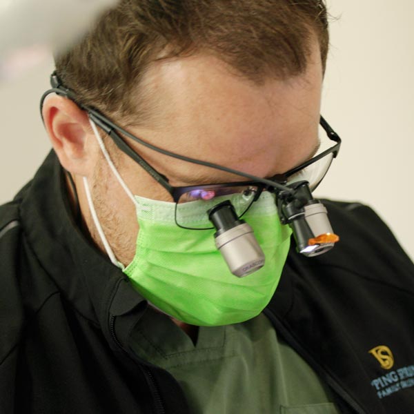 Dr. Christopher DeMarco wearing magnifying loupes and a green mask in Dripping Springs, TX